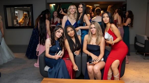 Eine Gruppe junger Schülerinnen der Queen Anne’s School posiert bei einer formalen Veranstaltung vor einem Spiegel mit Kunstwerken im Hintergrund.