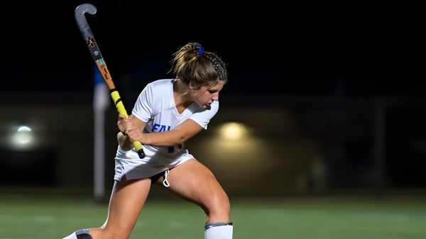 Eine Sportlerin der Queen Anne’s School spielt Feldhockey auf einem nachts schwach beleuchteten Spielfeld.