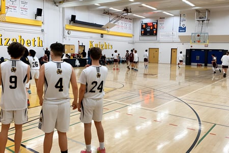 Eine Gruppe junger Basketballspieler steht auf dem Basketballfeld in der Sporthalle der Queen Elizabeth High School.