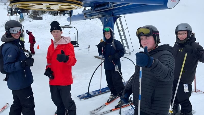 Eine Gruppe Schüler der Queen Elizabeth Regional High steht winterlich gekleidet am Skilift auf einem verschneiten Berg.