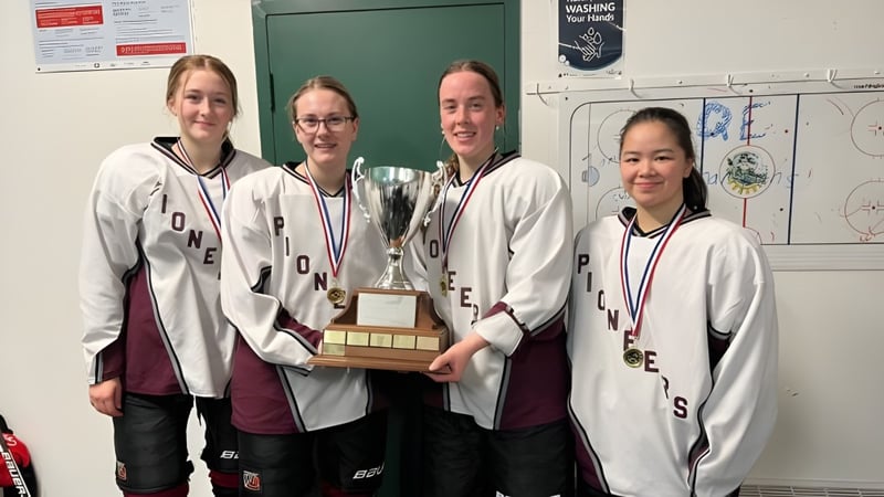 Die Sportmannschaft der Queen Elizabeth Regional High hält in der Umkleidekabine einen Pokal in den Händen.
