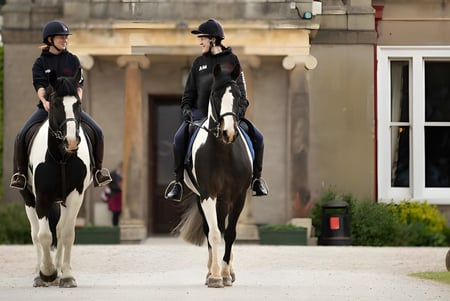 Zwei Reiter in Reitkleidung vor einem historischen Gebäude auf dem Gelände der Queen Margaret’s School.