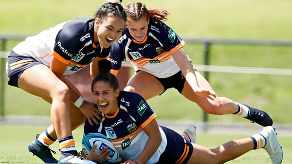Eine Gruppe von Rugbyspielerinnen spielt ein Tackle auf dem Sportfeld der Queen Margaret's School for Girls.