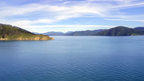 Ein ruhiger See mit Bergen und blauem Himmel in der natürlichen Umgebung der Queens High School.