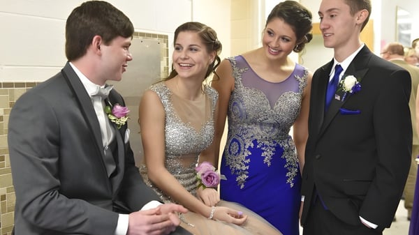 Vier Schüler der Queensbury High School stehen in festlicher Kleidung im Flur während eines Schulballs.