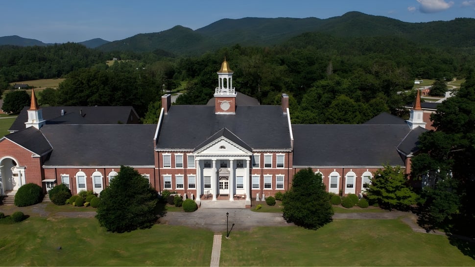 Das Backsteingebäude mit Uhrenturm der Rabun Gap-Nacoochee School ist von Grünflächen und Bergen umgeben.