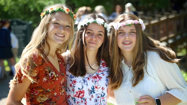 Drei Schülerinnen mit Blumenkränzen lächeln im Freien auf dem Campus der Rabun Gap-Nacoochee School.
