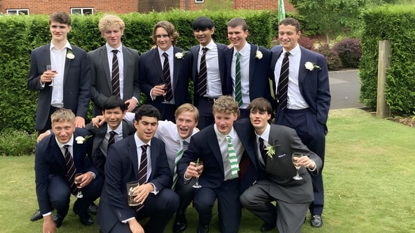 Eine Gruppe Schüler des Radley College posiert vor einem Backsteingebäude mit grüner Umgebung.