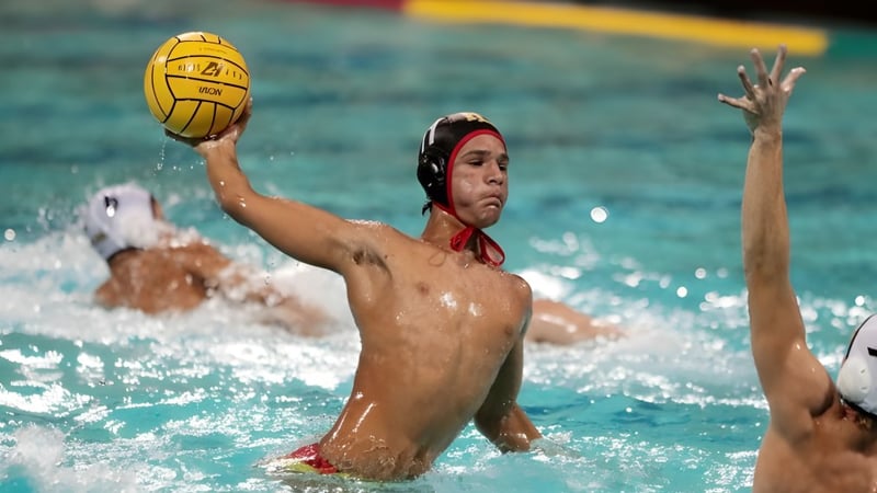 Ein Spieler des Radley College in roter Kappe schlägt im Wasserpolo während eines Spiels den gelben Ball.
