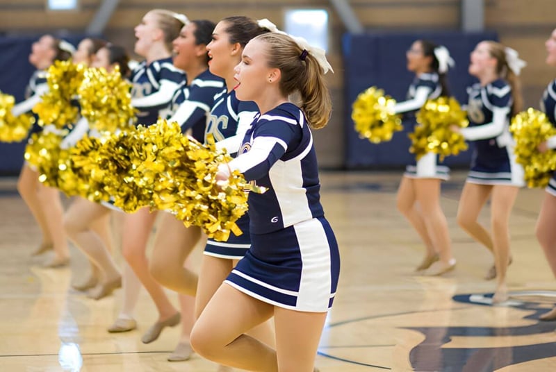Eine Gruppe Cheerleader der Rancho Solano Preparatory School führt mit gelben Pompoms auf dem Basketballfeld eine Performance auf.