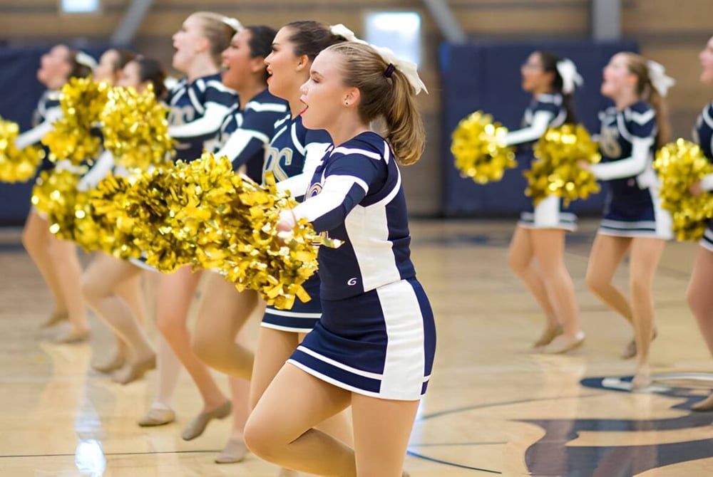 Eine Gruppe Cheerleader der Rancho Solano Preparatory School führt mit gelben Pompoms auf dem Basketballfeld eine Performance auf.