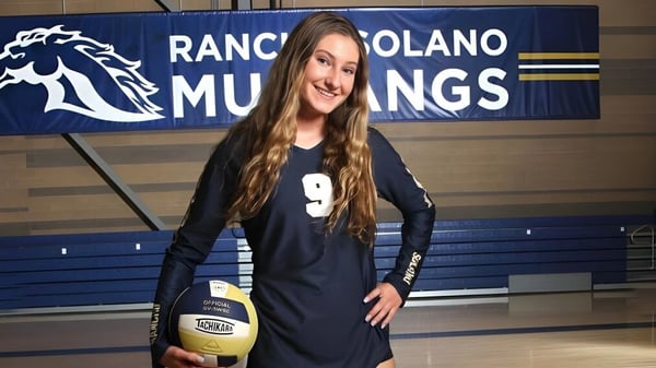 Eine Schülerin der Rancho Solano Preparatory School hält einen Volleyball vor einem Mustang-Banner.