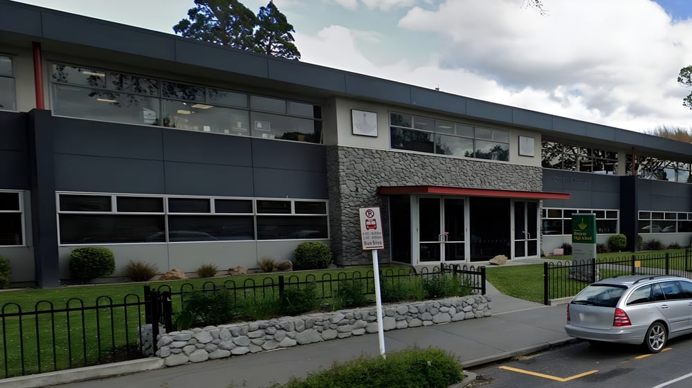 Das moderne mehrstöckige Gebäude der Rangiora High School mit Steinfassade steht umgeben von Grünfläche und einem geparkten Auto.