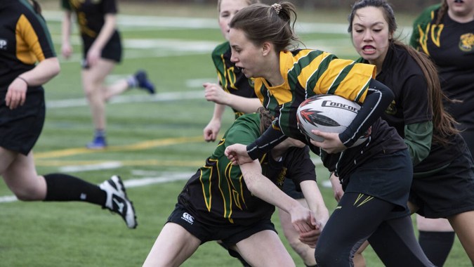 Weibliche Rugby-Spielerinnen kämpfen auf dem Rugbyfeld der Rathdown School um den Ball.