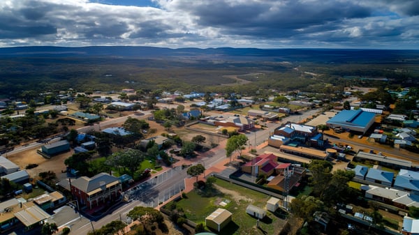 Blick auf eine Stadt in einer bergigen Landschaft unter wolkenverhangenem Himmel bei der Ravensthorpe District High School.