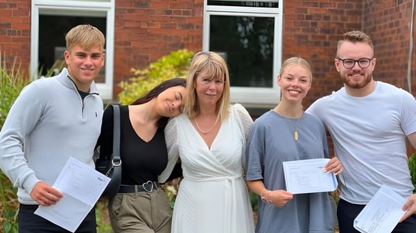 Vier Schülerinnen und Schüler der Read School stehen vor einem Backsteingebäude und halten Zertifikate.