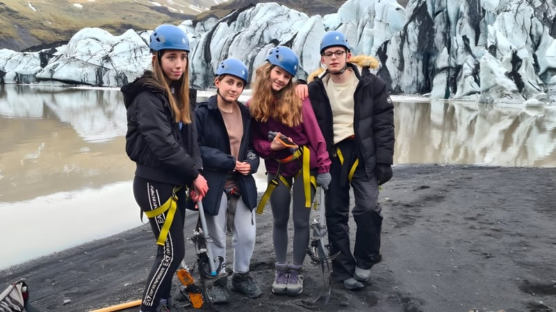 Schüler der Read School tragen Schutzkleidung und stehen an einem felsigen Strand mit Gletscher im Hintergrund.
