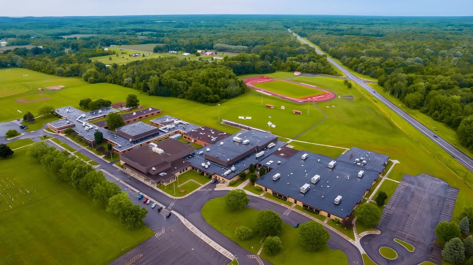 Landschaft mit Sportplatz und Gebäuden auf dem Gelände der Red Creek High School im ländlichen Raum.