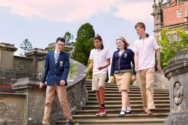 Schüler der Reddam House Berkshire gehen gemeinsam eine Steintreppe vor einem historischen Gebäude hinauf.