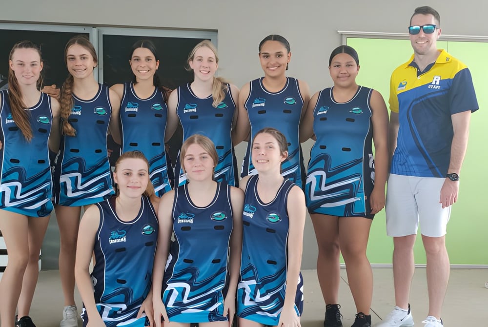 Eine Gruppe junger Athletinnen posiert in blauen und weißen Uniformen vor einem Gebäude auf dem Campus des Redlynch State College.