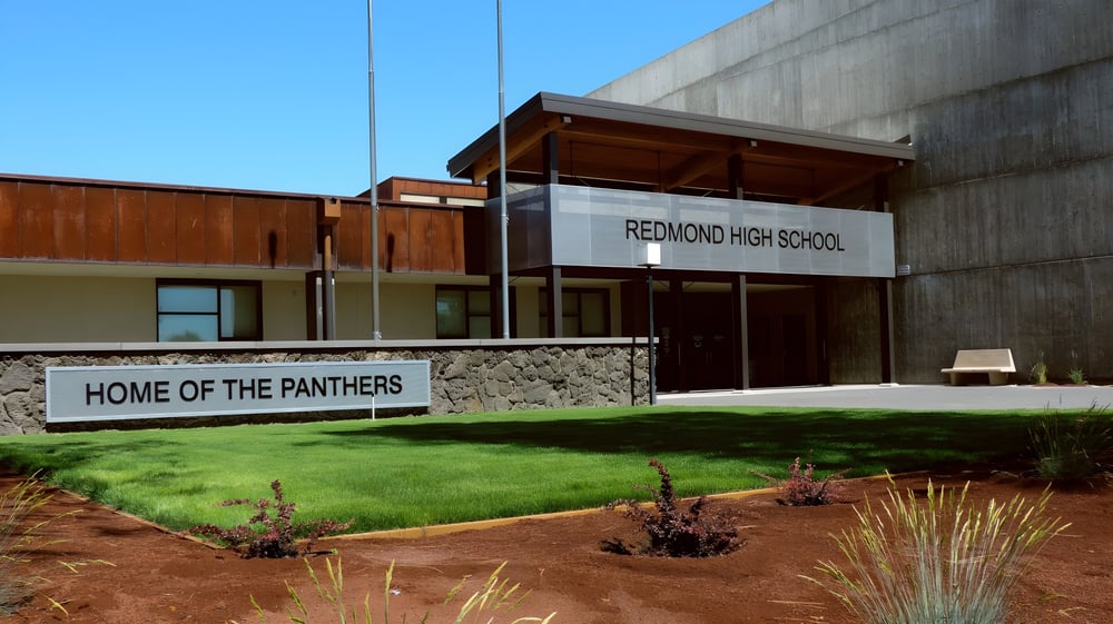 Das Schulgebäude der Redmond High School mit einem Schild 'Home of the Panthers' im Vordergrund.