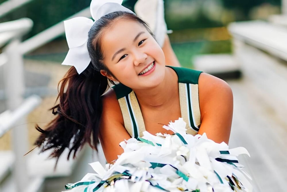 Eine Schülerin der Redmond High School mit weißer Haarschleife lächelt vor einem grünen Hintergrund.