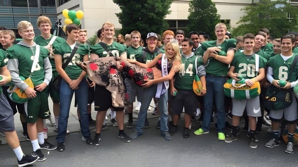 Schüler der Redmond High School versammeln sich vor einem Gebäude in grünen Sportuniformen mit Luftballons.