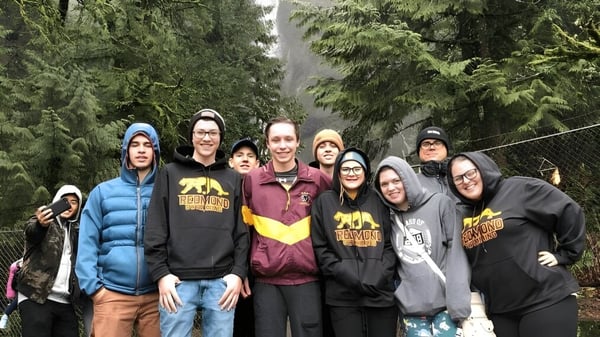 Eine Gruppe von Schülerinnen und Schülern steht im Wald auf dem Gelände der Redmond High School.