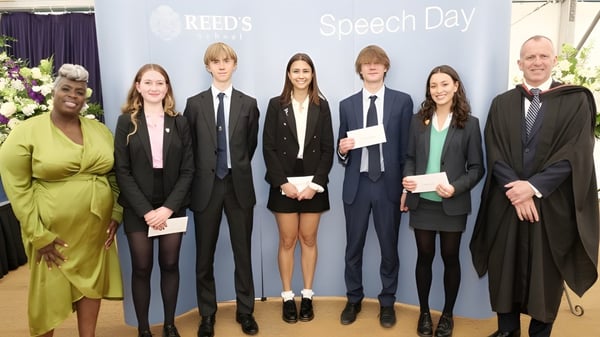 Schüler der Reed’s School stehen in formeller Kleidung vor dem Banner mit der Aufschrift Reed's Speech Day.