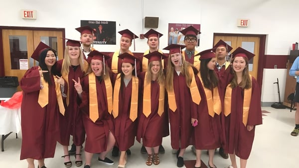 Eine Gruppe von Absolventen in regional School Unit N26 steht gemeinsam in einem Flur mit einem Ausgangsschild im Hintergrund.