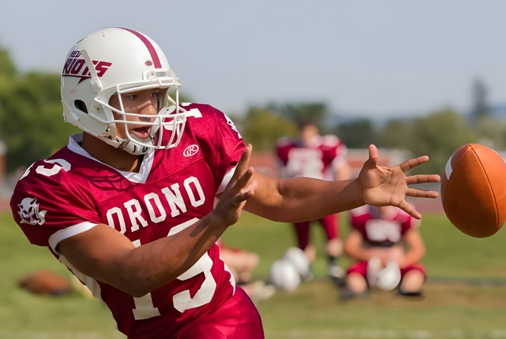 Ein Fußballspieler in rotem Trikot fängt den Ball auf dem Spielfeld der Regional School Unit N*26.