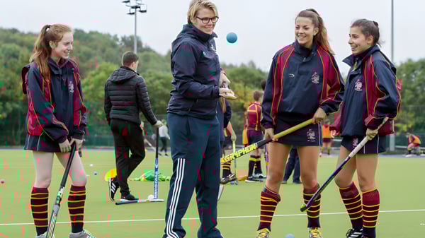 Eine Gruppe Schülerinnen des Rendcomb College steht in Sportuniformen auf einem Feld vor einem Waldgebiet.