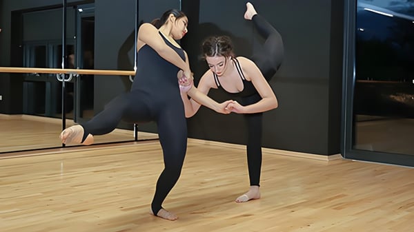 Zwei Frauen in Sportkleidung üben gemeinsam eine Yoga-Pose im Studio des Rendcomb College.
