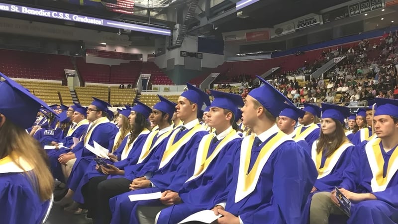 Abschlussfeier mit Absolventen der Resurrection Catholic School in blauen und gelben Talaren in einer großen Halle.