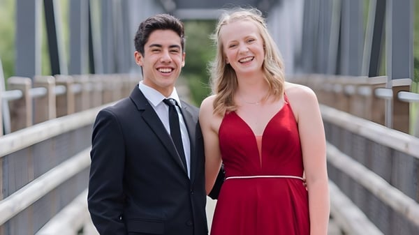 Ein junges Paar steht lächelnd auf einer Brücke auf dem Gelände der Revelstoke Secondary School.