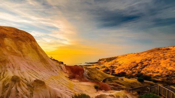 Ein landschaftliches Bild mit farbenfrohen Klippen und einem Weg vor der Küste, ohne direkten Bezug zum Reynella East College.