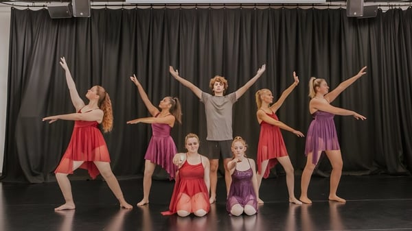 Eine Gruppe von Tänzerinnen und Tänzern führt auf der Bühne am Reynella East College eine Tanzaufführung in bunten Kostümen auf.