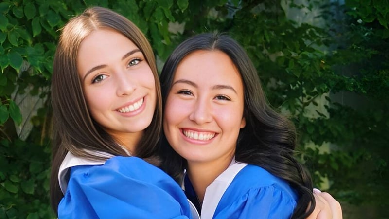 Zwei Schülerinnen der Reynolds Secondary School stehen zusammen vor einem grünen Hintergrund und lächeln.