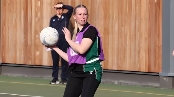 Eine Schülerin von RGS Surrey Hills hält auf dem Sportfeld mit Holzwand einen Rugbyball.