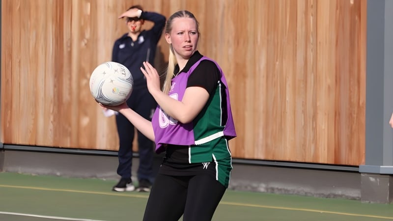 Eine Schülerin von RGS Surrey Hills hält auf dem Sportfeld mit Holzwand einen Rugbyball.