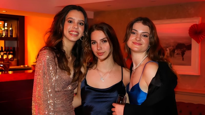 Drei Schülerinnen der RGS Surrey Hills posieren zusammen in einem stilvoll beleuchteten Barbereich.