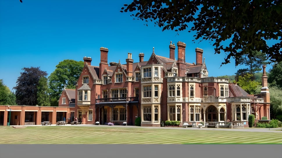 Das viktorianische Herrenhaus mit Türmen und Schornsteinen auf dem Gelände der RGS Surrey Hills Box Hill School ist von einem gepflegten Rasen umgeben.