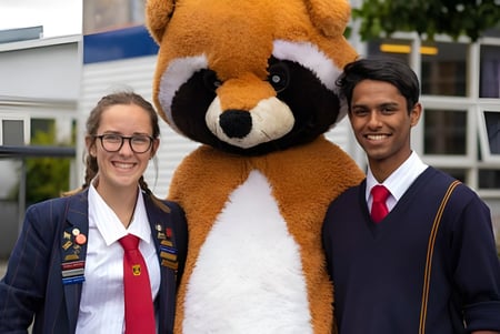 Zwei Personen in formeller Kleidung stehen vor einer großen Tier-Skulptur auf dem Campus der Riccarton High School.
