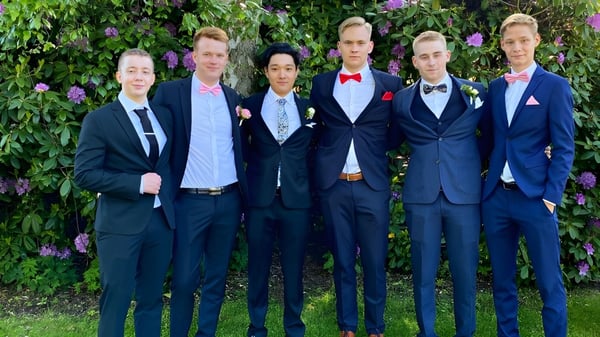 Eine Gruppe Schüler des Rice College steht in einem grünen Garten mit blühenden Blumen.