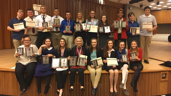 Eine Gruppe von Schülern der Richmond High School steht mit Auszeichnungen vor einer Bühne.