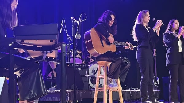 Eine Gruppe von Schülern der Richmond Regional High School spielt gemeinsam auf der Bühne mit akustischer Gitarre und Gesang.