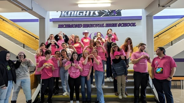 Eine Gruppe von Schülerinnen steht gemeinsam vor einem Banner der Richmond Regional High School.
