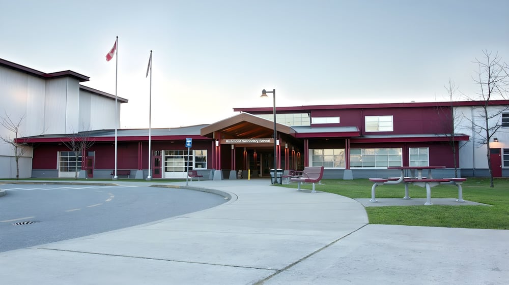 Das moderne mehrstöckige Schulgebäude der Richmond Secondary School mit kanadischer Flagge außerhalb.