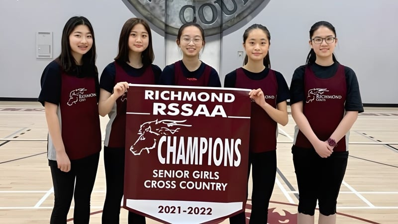Fünf Schülerinnen der Richmond Secondary School halten ein Banner als RSSAA Champions im Seniorenmädchen Cross Country 2021-2022.