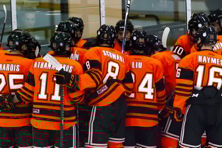 Eine Gruppe von Hockeyspielern in orangen Trikots steht gemeinsam vor einem Gebäude auf dem Campus des Ridley College.